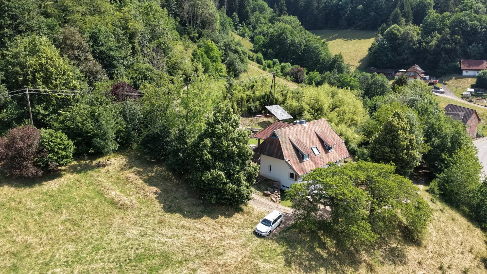 Luftaufnahme: das Haus der Ferienwohnung Schrödter im Schwarzwaldtal, umgeben von Wiesen und bewaldeten Hängen